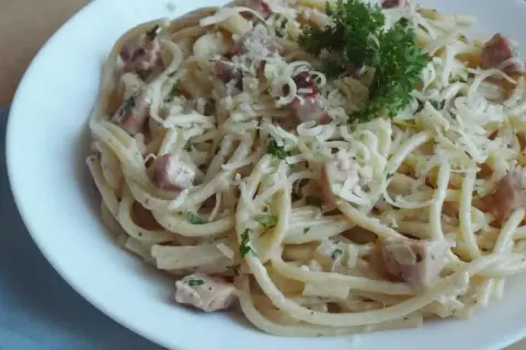 Spaghetti carbonara - przepis oryginalny ze śmietaną. Pyszne danie z makaronem, boczkiem i serem, udekorowane natką pietruszki.
