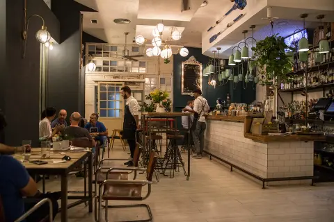 Gente disfrutando de tapas en Almería, con camareros sirviendo y un ambiente acogedor.