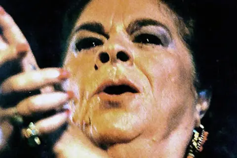 Primer plano de una mujer con maquillaje dramático, labios entreabiertos y mano levantada. Se especula de que murió la Paquera de Jerez.