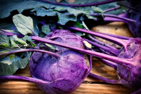 Gros plan sur des choux-raves violets aux feuilles vertes, posés sur du bois. Un légume coloré prêt à être cuisiné.