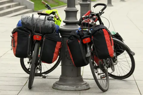 Dwa rowery z sakwami i bagażami, gotowe do wyprawy. Widać śpiwór, kask i inne rzeczy, które warto zabrać na wyprawę rowerową.