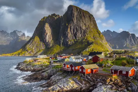 Traumhafte norwegen route 2 wochen: Rote Fischerhäuser am Fuße steiler Berge an der Küste.