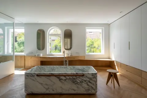 Baño moderno con bañera de mármol, lavabos y armarios de madera. Un ejemplo de reformas casas de pueblo con estilo.