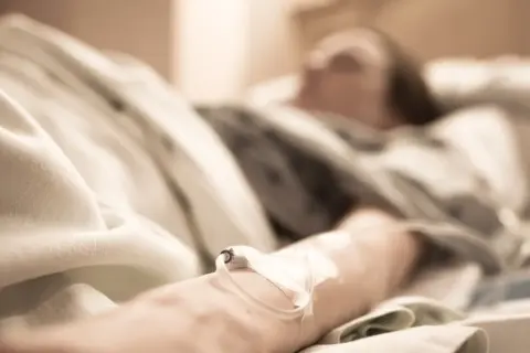 Ostatnie chwile, ostatnie pragnienia. Ręka z wenflonem, pod kołdrą szpitalną, czeka na spełnienie zachcianek przed śmiercią.