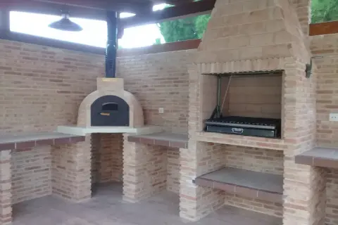 Un barbecue in muratura fai da te con forno a legna e griglia, perfetto per cene all'aperto.