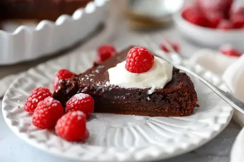 En bit kladdkaka med vispad grädde och hallon, perfekt för ett kladdkaka recept.