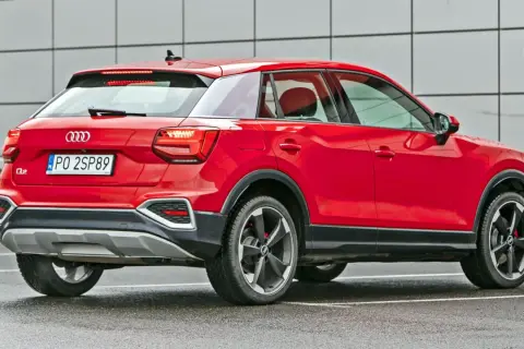 Czerwone Audi Q2 z polskimi tablicami PO 2SP89. Kompaktowy SUV, którego wymiary sprawiają, że jest idealny do miasta.