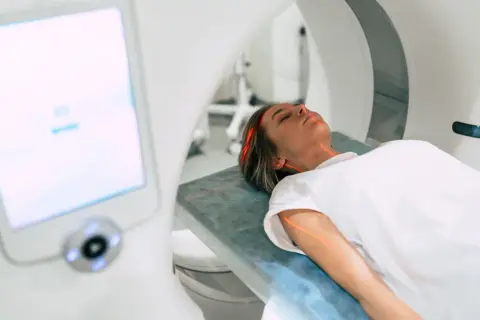 Kobieta leży na stole do rezonansu magnetycznego. Czerwone linie lasera wskazują obszar badania. Ważne są rezonans magnetyczny przeciwwskazania.