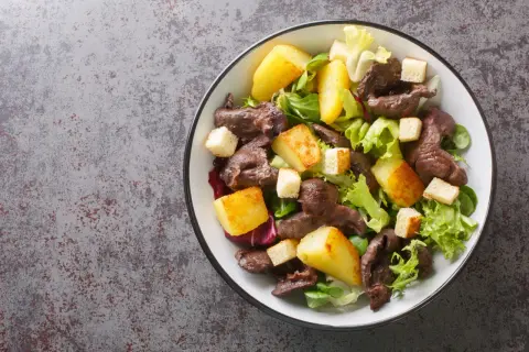 Salade de gésiers savoureuse avec pommes de terre rôties, croûtons et salade verte. Un délice pour les papilles.