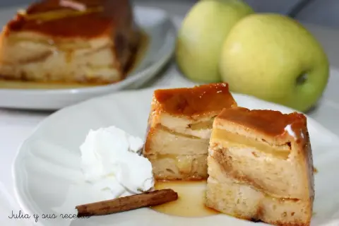 Delicioso pudin de manzana con caramelo, crema batida y canela. Dos porciones servidas en un plato blanco, con dos manzanas verdes al fondo.