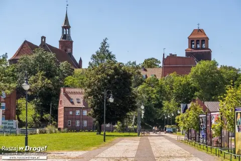 Tczew atrakcje: zabytkowy kościół, urokliwe kamieniczki i zielony park. Spacerowicze cieszą się słonecznym dniem.