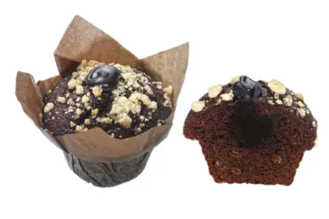 Zwei saftige triple chocolate muffins, einer im Papierförmchen, der andere angeschnitten, mit Schokostückchen und Streuseln.