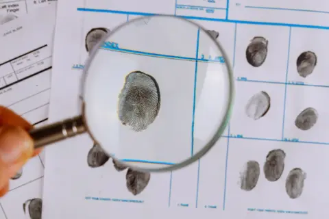 Lupe über Fingerabdrücken auf einem Formular, ein Detail für das kriminologie studium.