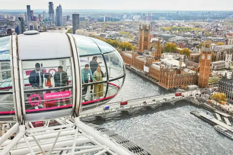 Ludzie podziwiają panoramę Londynu z kapsuły diabelskiego młyna. Widać Tamizę, Parlament i Big Bena.