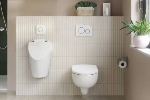 Dwa wiszące WC, jedno wyżej, drugie niżej, pokazują różnice w wysokości WC od podłogi. Obok prysznic i uchwyt na papier.