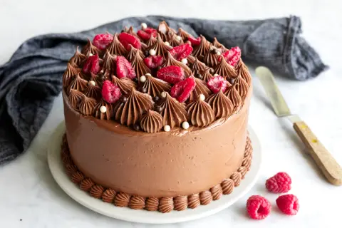En lyxig chokladtårta med hallon och chokladdekorationer, redo att avnjutas.