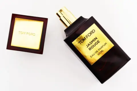 Elegancka butelka perfum Tom Ford Jasmin Rouge z złotą etykietą i korkiem.