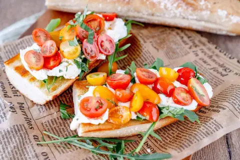 Geröstetes Brot mit Burrata, Kirschtomaten und Rucola.