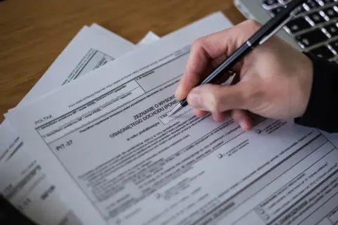 Dłoń z długopisem wypełnia PIT-37. Zastanawiasz się, komu przysługuje ulga na dziecko? Sprawdź formularz!