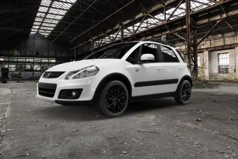 Vit Suzuki SX4 med svarta fälgar står i en övergiven lagerlokal. Kanske ett problem med att hitta en ny ägare?