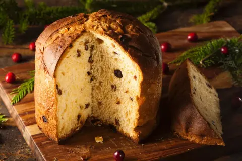Ein köstlicher Panettone, perfekt für ein sizilianisches Panettone Rezept, mit Rosinen und Nüssen, dekoriert mit Cranberries und Tannenzweigen.