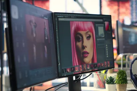 Post-production définition : un écran affiche un portrait de femme avec une perruque rose, en cours d'édition.