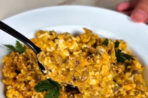 Pyszna pasta z makreli i twarogu, idealna na kanapki. Na czarnej łyżce widać kawałki ryby i sera, ozdobione natką pietruszki.