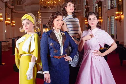 Vier Frauen in farbenfrohen Outfits, die den musical dress code verkörpern. Eine in Gelb, eine in Blau, eine in gestreiftem Oberteil und eine in Rosa.