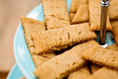 En hög med gyllene kolakakor på en blå bricka. Perfekt för fikat, här är ett enkelt kolakakor recept.
