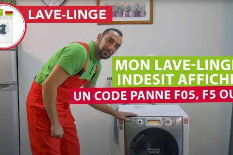 Un homme en salopette rouge devant un lave-linge Indesit 9 kg qui affiche un code panne F05.