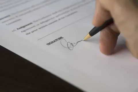 Dłoń podpisuje dokument. Złożenie podpisu może być początkiem sprawy sądowej, czyli pozwu.