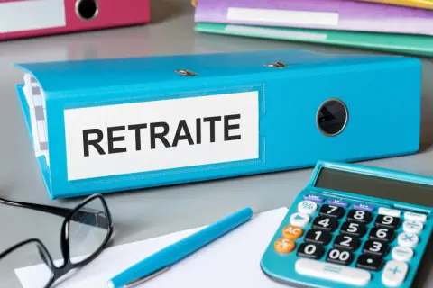 Dossier bleu "Retraite" sur un bureau, avec une calculatrice, des lunettes et un stylo. L'aspa montant est peut-être dans ce dossier.
