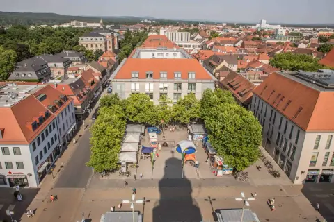 Marktplatz in Erlangen mit Ständen und Bäumen. Ein Schatten wirft sich über den Platz, vielleicht ein Geheimtipp für Fotografen.