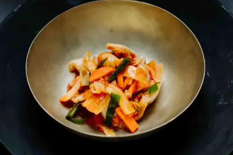 Frisch zubereitetes asiatisches Essen: Kimchi mit Karotten und Frühlingszwiebeln in einer Schüssel.