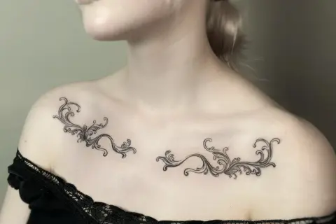 Delikatny tatuaż ornament damski na obojczykach, przypominający koronkę.
