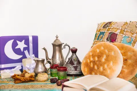 Przygotowania do iftaru: ozdobne prezenty, tradycyjny czajniczek, daktyle, pieczywo i książka.