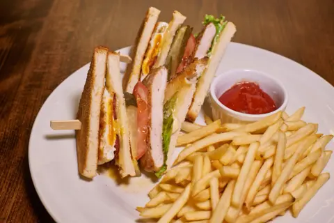 Idealne przekąski do piwa: chrupiące frytki i soczyste kanapki club sandwich z kurczakiem, bekonem i jajkiem.