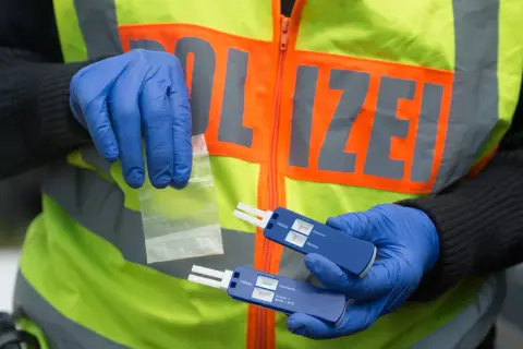 Polizist mit Handschuhen hält Drogenprobe und Tests für Drogen am Steuer.