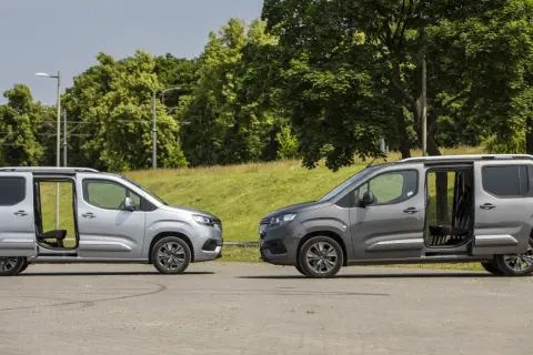Dwa samochody Toyota Proace City Long w kolorach srebrnym i grafitowym stoją obok siebie z otwartymi drzwiami, ukazując wnętrze.