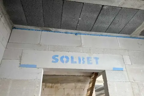 Ściana z bloczków z widocznym logo "SOLBET" i niebieską pianką montażową, która zapobiega pękaniu i zapewnia dylatację.