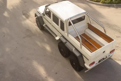 Biały Mercedes 6x6 z drewnianą paką, gotowy na każdą przygodę.