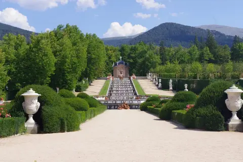 Jardín de la Granja de San Ildefonso, Madrid. Escalera de agua con estatuas y fuentes, rodeada de vegetación y montañas.