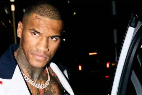 Boxaren Conor Benn med tatueringar och en diamantkedja, redo för en kväll ute.