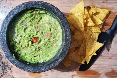 Färdiggjord guacamole i en mortel, redo att serveras med tortillachips. Ett enkelt guacamole recept för alla.