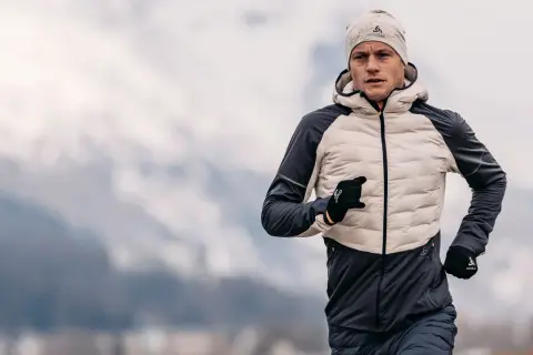 Un homme court par temps froid, portant une veste pour courir l'hiver, un bonnet et des gants.