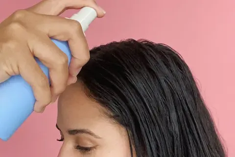 Una mano aplica sérum en el cabello oscuro. Descubre para qué sirve el sérum pelo y luce una melena radiante.