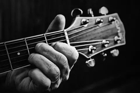 Dłoń z pierścionkiem na serdecznym palcu chwyta akord na gryfie gitary. Powstają piękne utwory na gitarę.