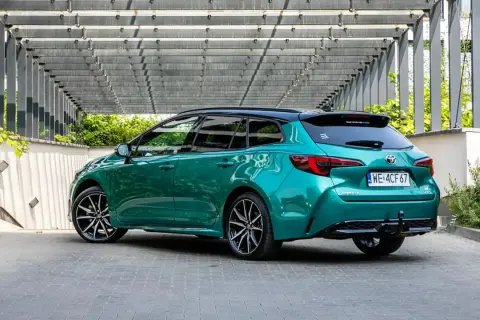 Zielona Toyota Corolla kombi z czarnym dachem, zaparkowana pod nowoczesną pergolą. Sprawdź atrakcyjną toyota corolla cena!