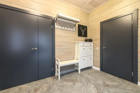 Stylowa aranżacja mieszkania 30m2: ciemne drzwi, biała szafka na buty z ławką i wieszak.