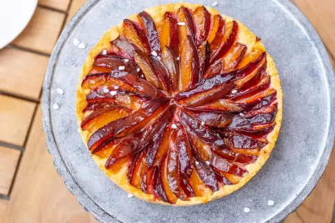 Ein köstlicher Zwetschgenkuchen auf Hefeteig, mit saftigen Pflaumenstücken und einem glänzenden Zuckerguss, verlockend präsentiert.